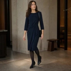 Kvinde i marineblå kjole og sorte strømpebukser på vej gennem en elegant lobby