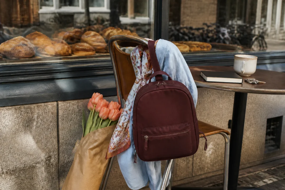 Bordeaux lille rygsæk på caféstol med blå skjorte, tørklæde og tulipaner