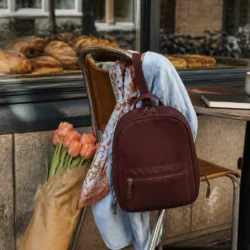 Bordeaux lille rygsæk på caféstol med blå skjorte, tørklæde og tulipaner