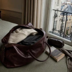 Åben bordeaux weekendtaske pakket til en storbyrejse ved et vindue