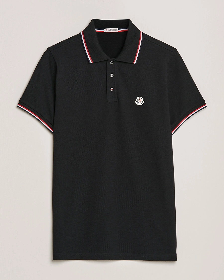 Sofistikeret sort Moncler polo-shirt med fin tricolore-kant på kraven, der tilfører et subtilt designerpræg til et casual look.