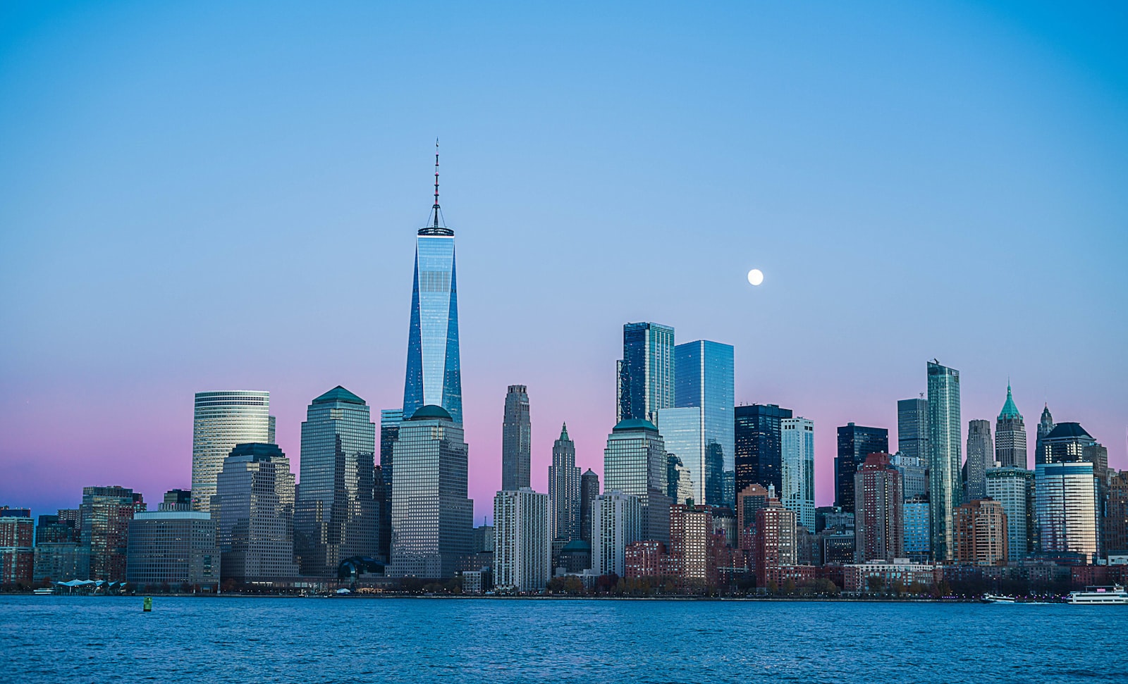 Manhattan skyline med One World Trade Center set fra vandet ved skumring