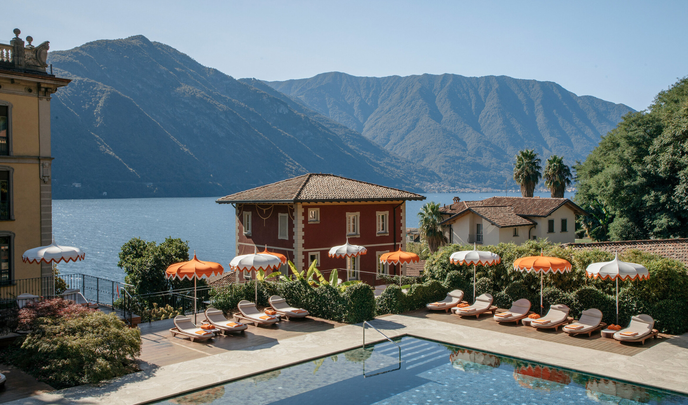 Flowers Pool på Grand Hotel Tremezzo med orange-hvide parasoller, Como-søen og Grigne-bjergene
