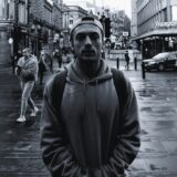 Mand i grå hoodie på våd bygade, editorial streetstyle