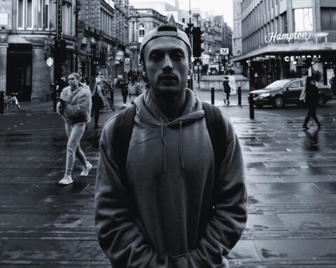 Mand i grå hoodie på våd bygade, editorial streetstyle