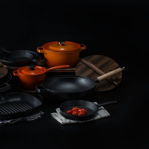 Støbejernsgryder og pander på mørk baggrund