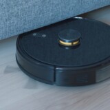 Sort robotstøvsuger på trægulv ved sofa