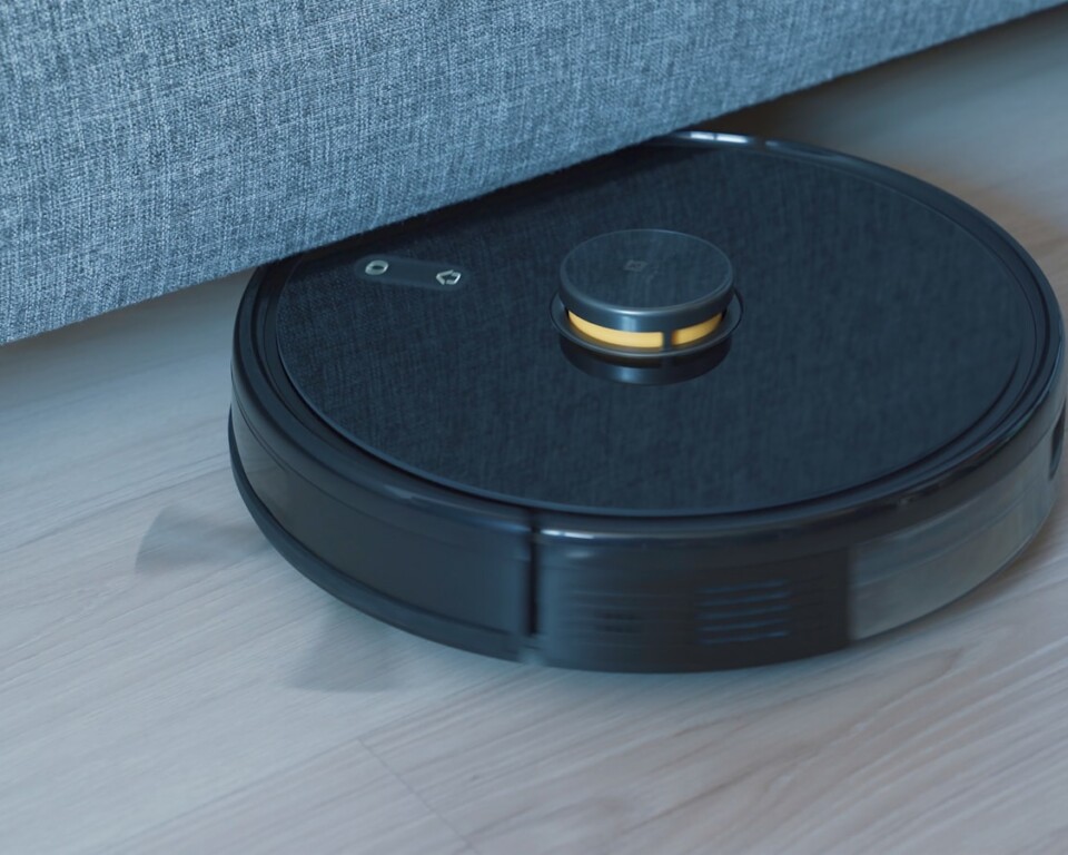 Sort robotstøvsuger på trægulv ved sofa