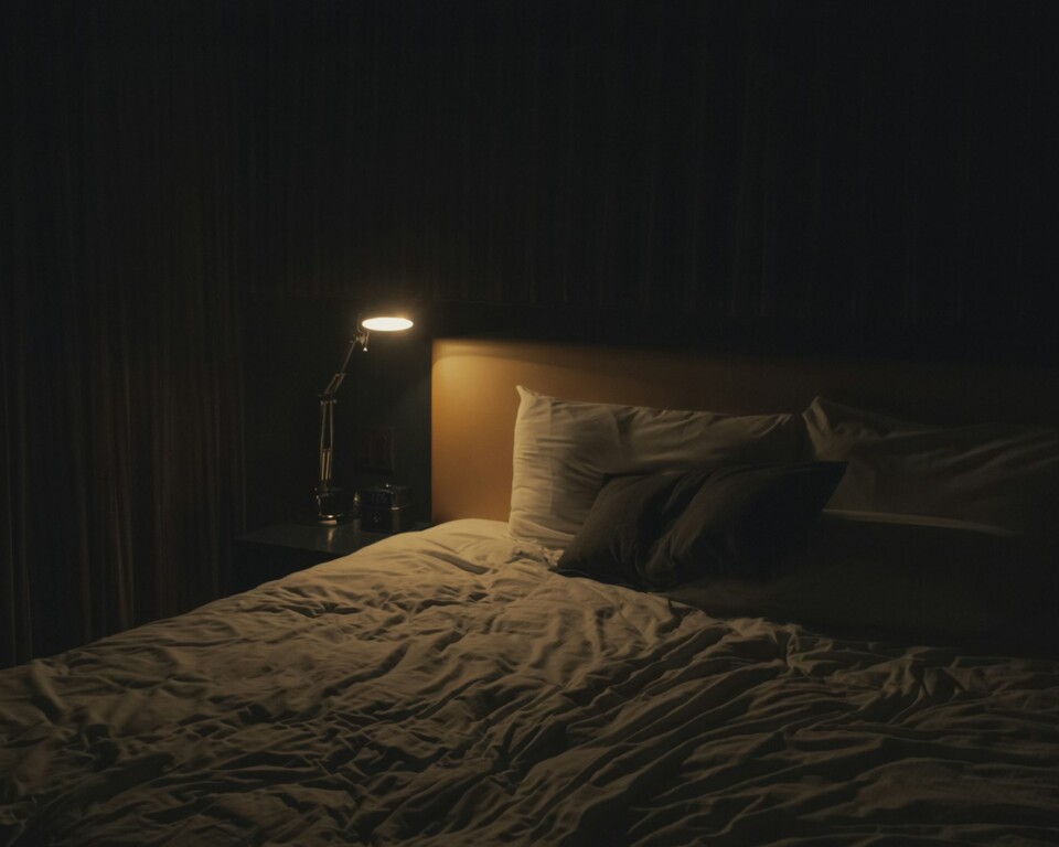 Mørkt soveværelse med varm lampe ved siden af seng