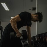 Mand træner med håndvægt i fitnesscenter