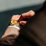 Mand i jakkesæt justerer et guldfarvet armbåndsur