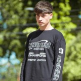 Mand i grafisk sort sweatshirt og løse jeans på en grøn villavej