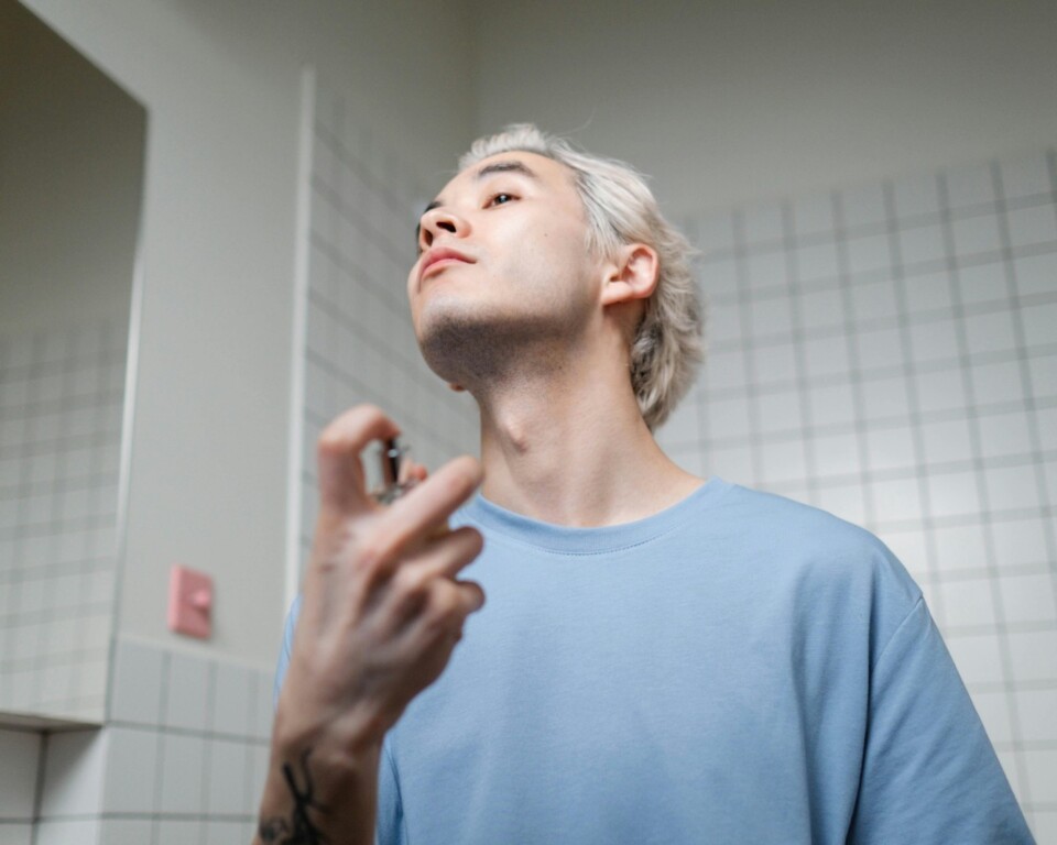 Mand der påfører parfume foran spejlet som cover til artikel om Hugo Boss parfume til mænd