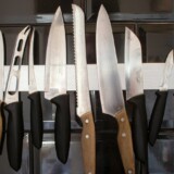 Køkkenknive på en magnetisk knivliste på en mørk flisevæg