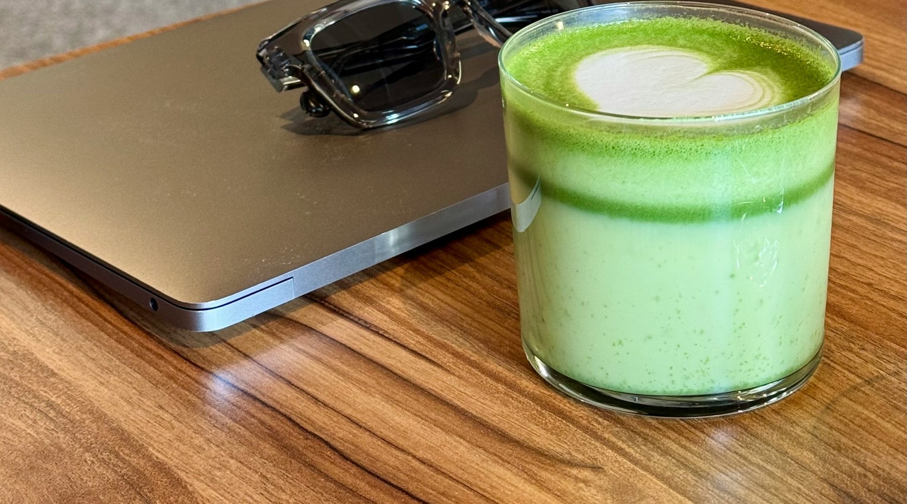 Matcha, laptop og solbriller på et arbejdsbord