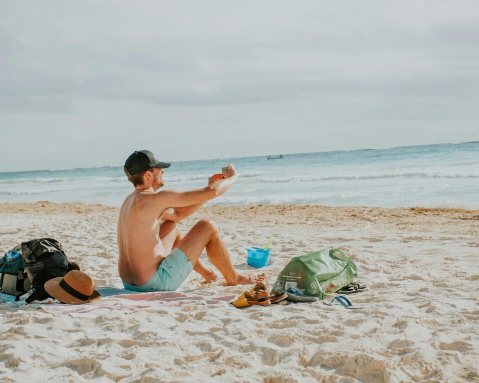 Mand på stranden med sol og bar hud