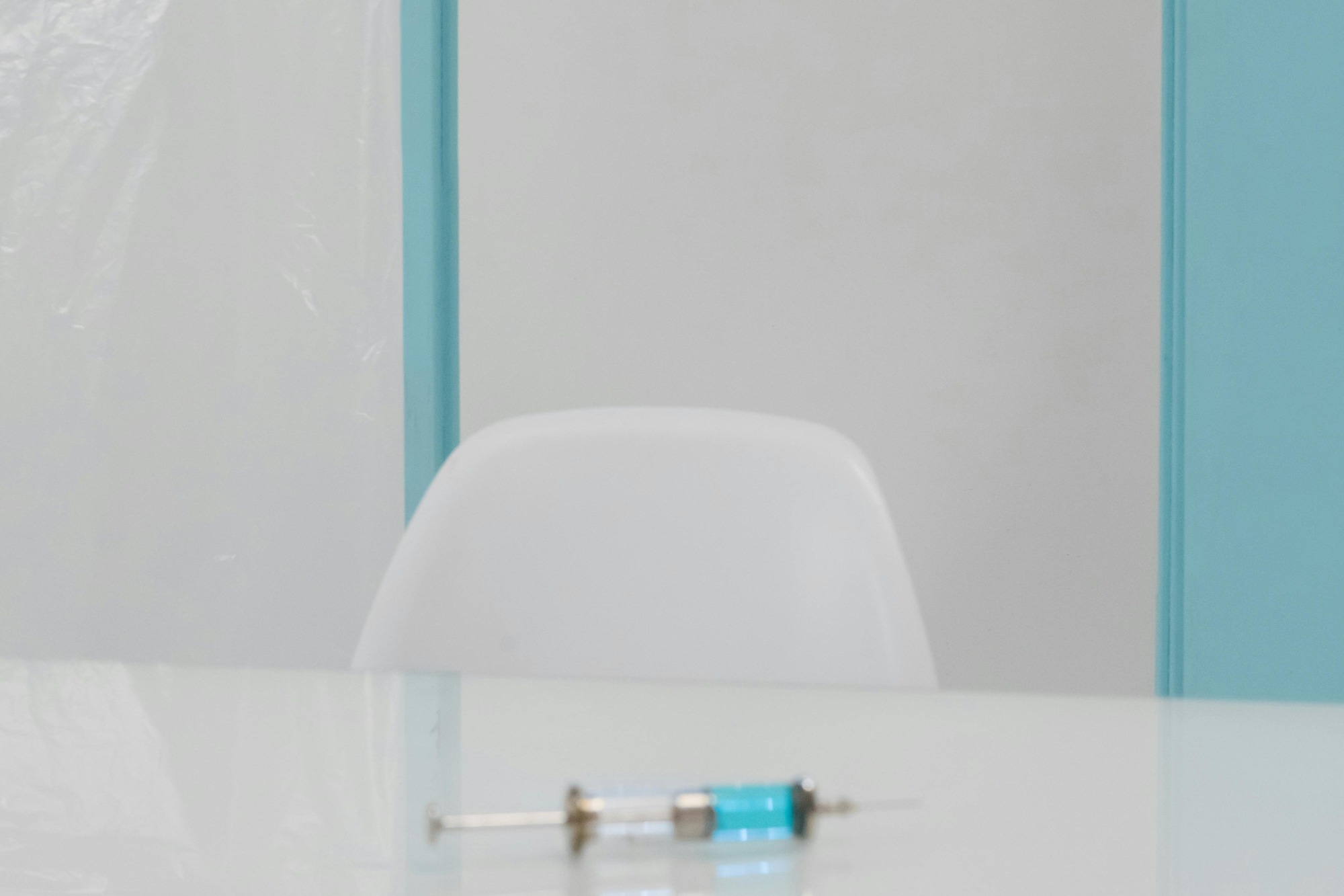 Sprøjte på et minimalistisk laboratoriebord med blå sterilt lys