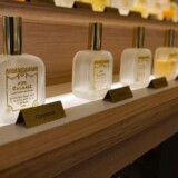 Parfumeflasker på oplyst hylde som redaktionelt cover til artikel om Versace parfume til mænd