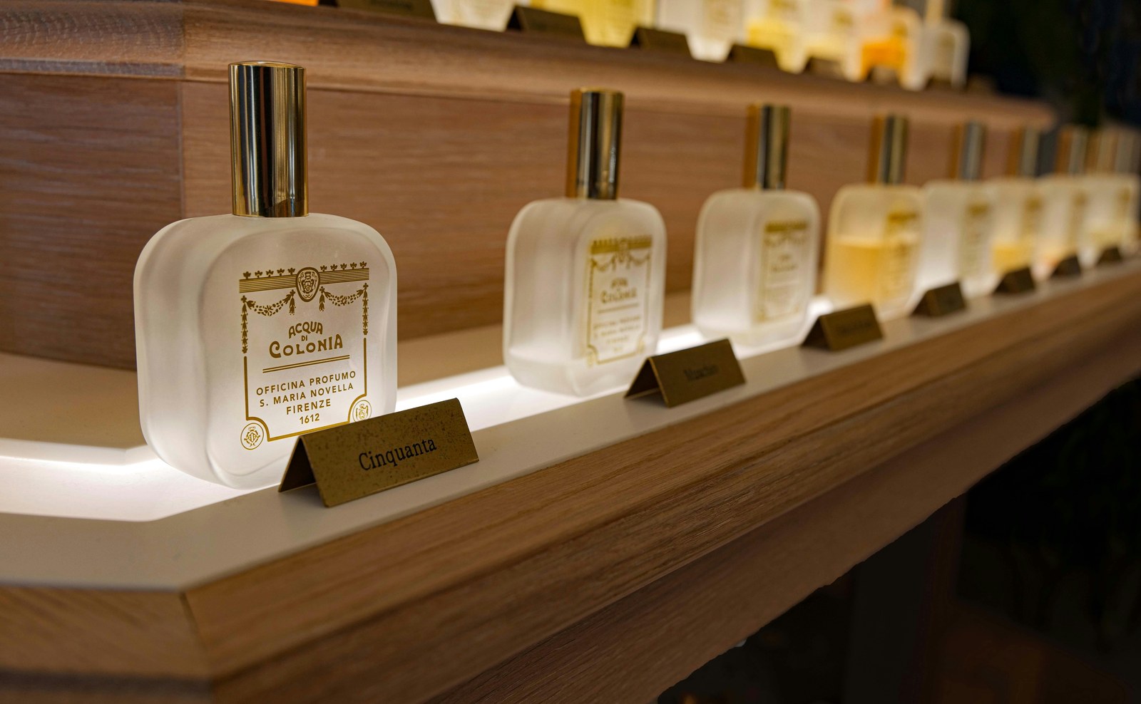Parfumeflasker på oplyst hylde som redaktionelt cover til artikel om Versace parfume til mænd