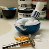 Barberskål, barberkost og skraber med barberskum på badeværelse