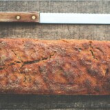 Brød og brødkniv på et træbræt i et køkken