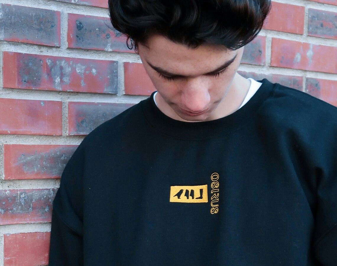 Mand i sort crewneck sweatshirt foran rød mur