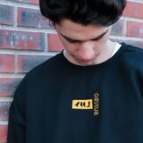 Mand i sort crewneck sweatshirt foran rød mur