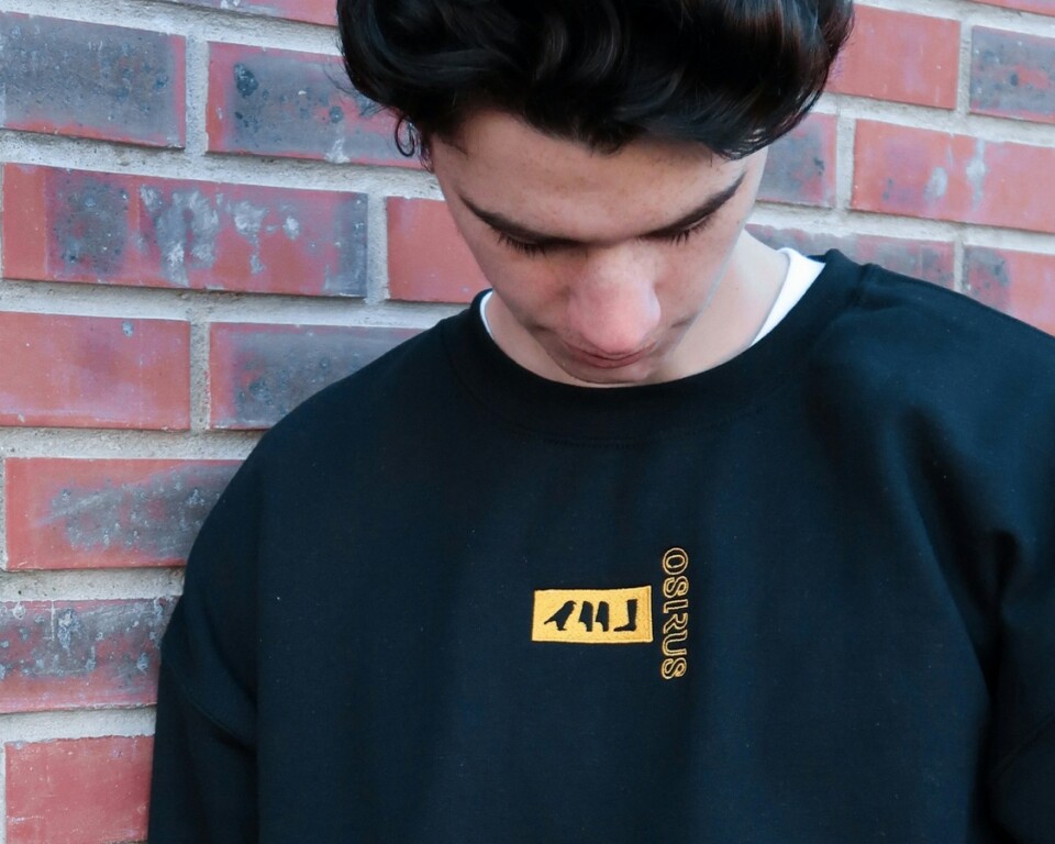 Mand i sort crewneck sweatshirt foran rød mur