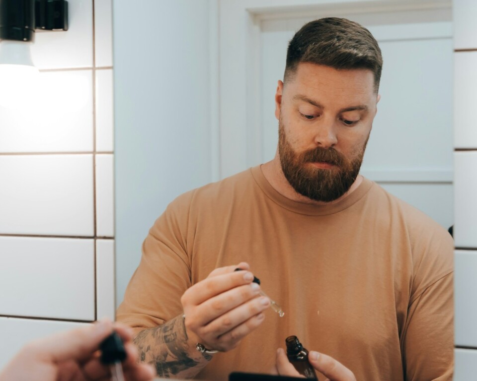 Mand foran badeværelsesspejl med serum som cover til artikel om øjencreme til mænd