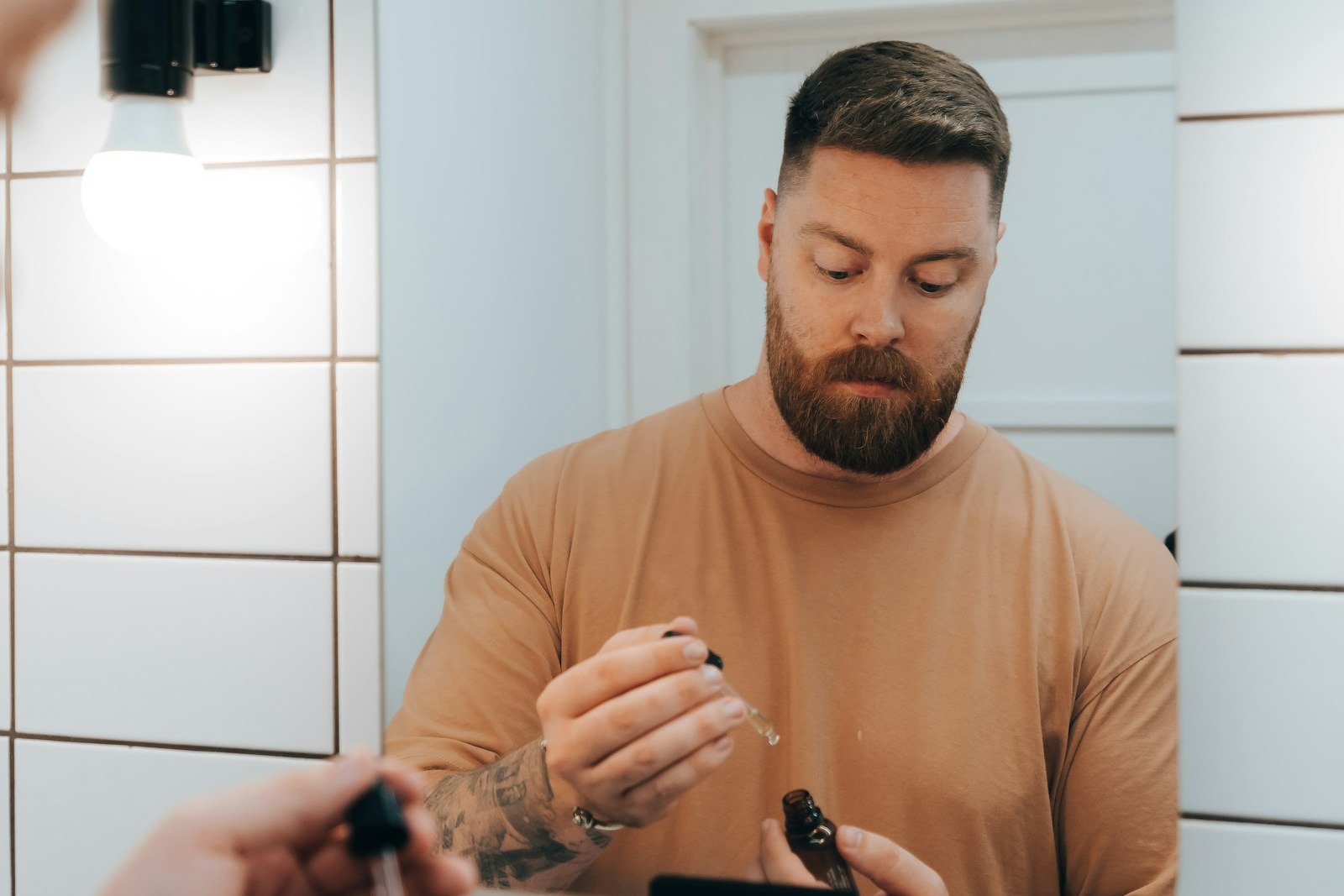Mand foran badeværelsesspejl med serum som cover til artikel om øjencreme til mænd