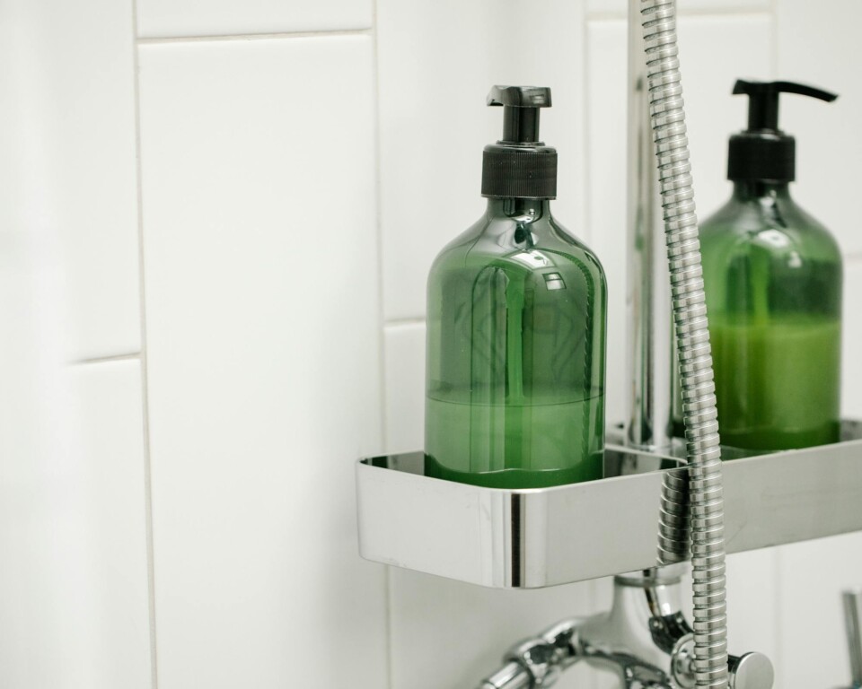 Grønne shower gel-dispensere på hylde i en bruseniche