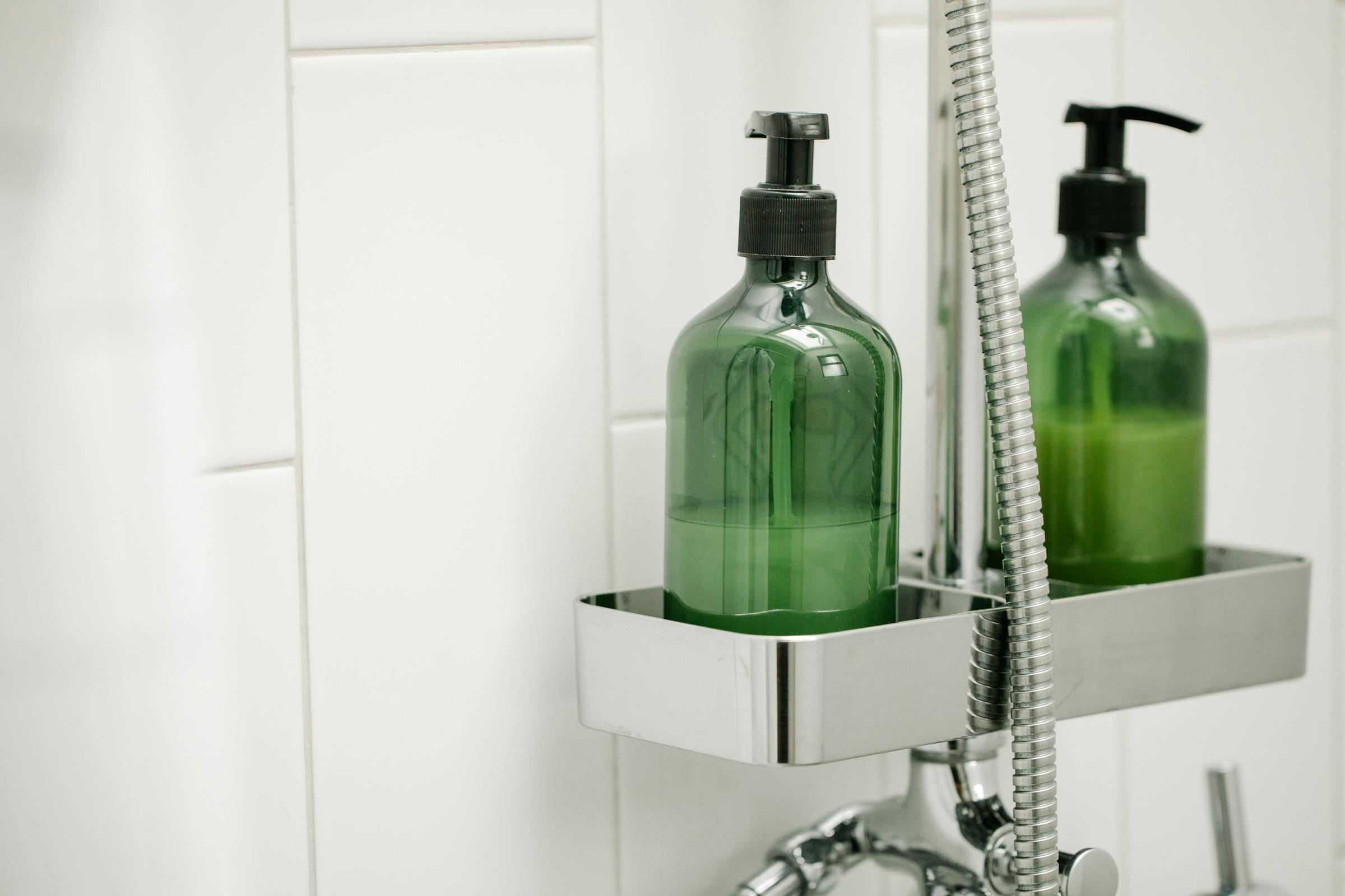 Grønne shower gel-dispensere på hylde i en bruseniche