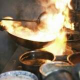 Flammer omkring en wok på et varmt komfur
