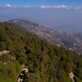 Bjerglodges i de grønne bakker med Himalaya i horisonten i Nepal