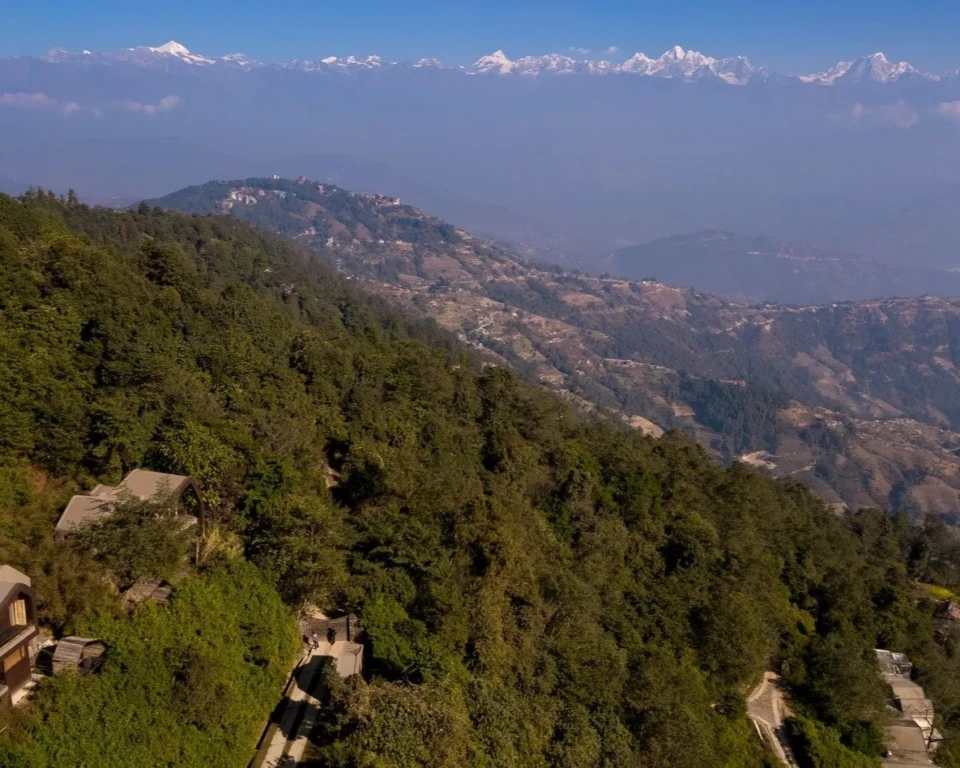 Bjerglodges i de grønne bakker med Himalaya i horisonten i Nepal