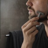 Mand former en skarp skægkant med klar barbergel og safety razor