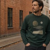 Mand i mørkegrøn grafisk sweatshirt på en københavnsk gade om efteråret
