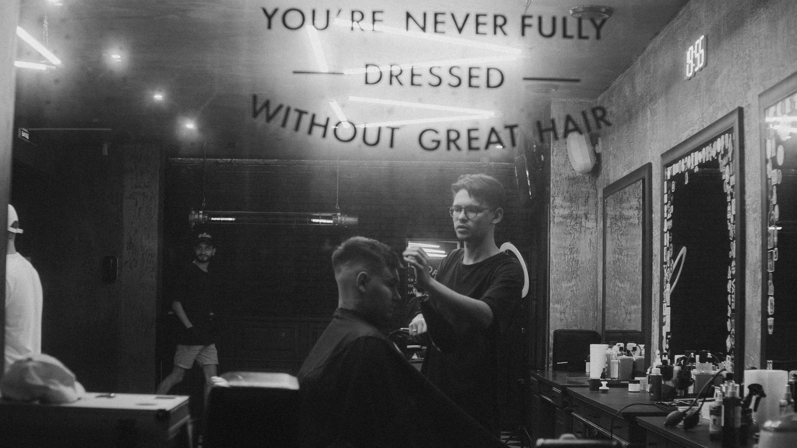 Barber styler hår i barbershop som cover til artikel om hårvand til mænd