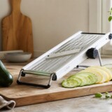 Mandolinjern med tynde grøntsagsskiver på køkkenbord