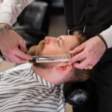 Barber bruger kam og saks til at rette skæg i en barbershop
