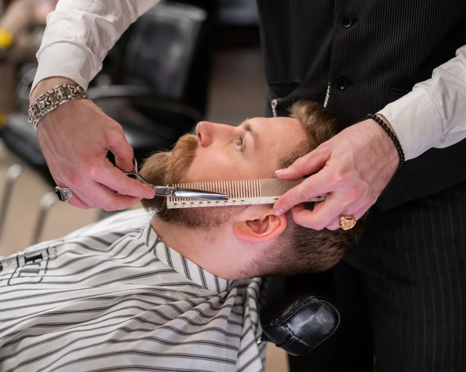 Barber bruger kam og saks til at rette skæg i en barbershop