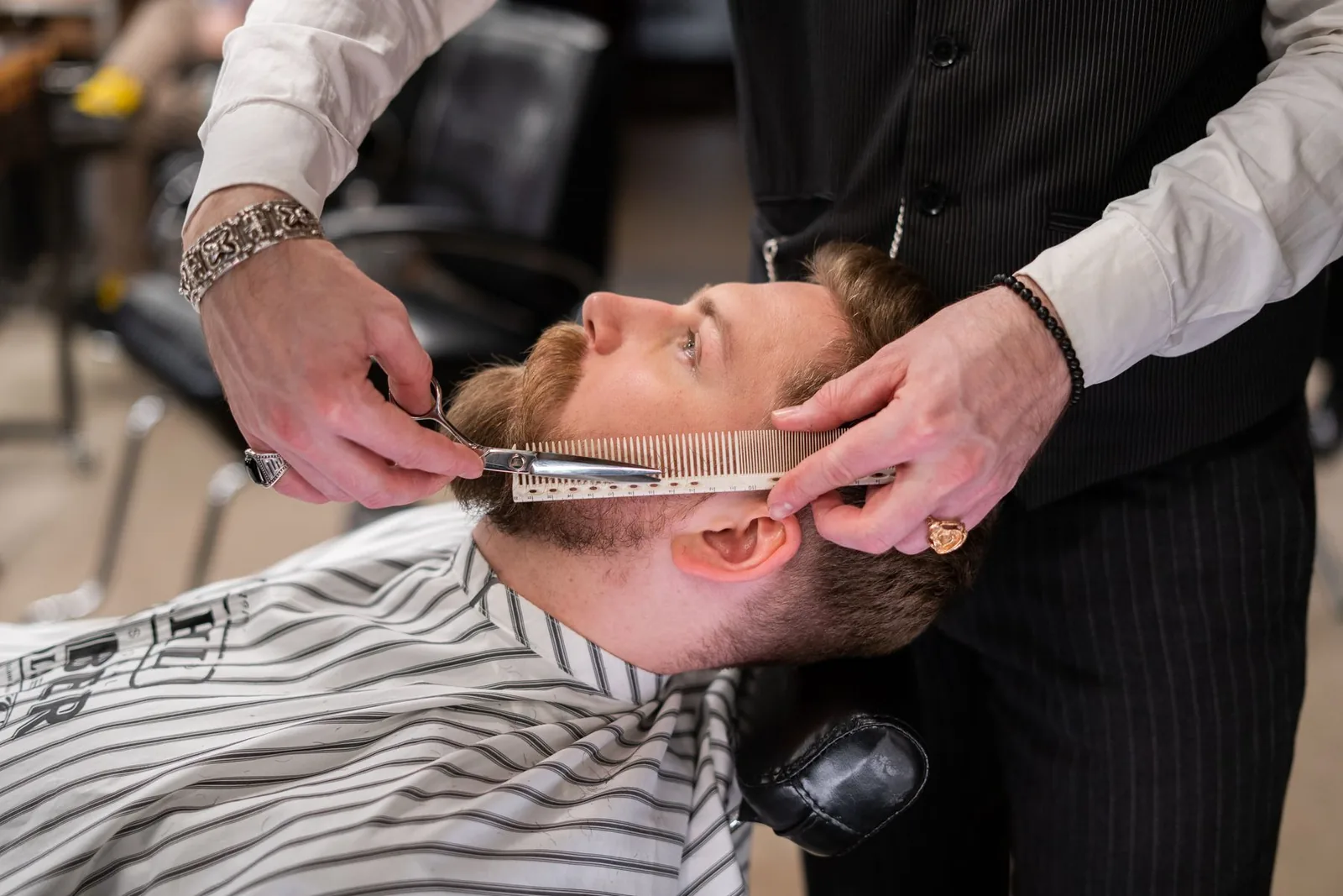 Barber bruger kam og saks til at rette skæg i en barbershop