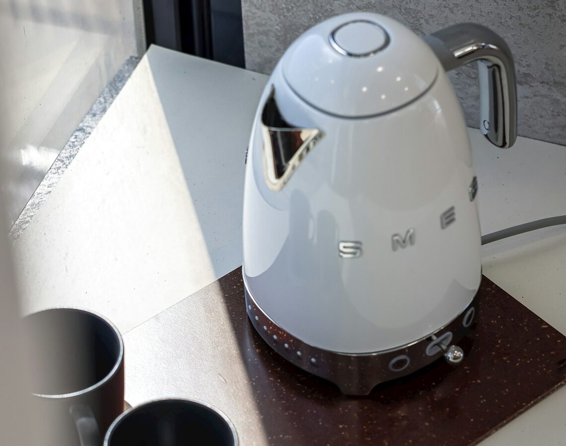 Hvid Smeg elkedel på køkkenbord med kopper og vindueslys