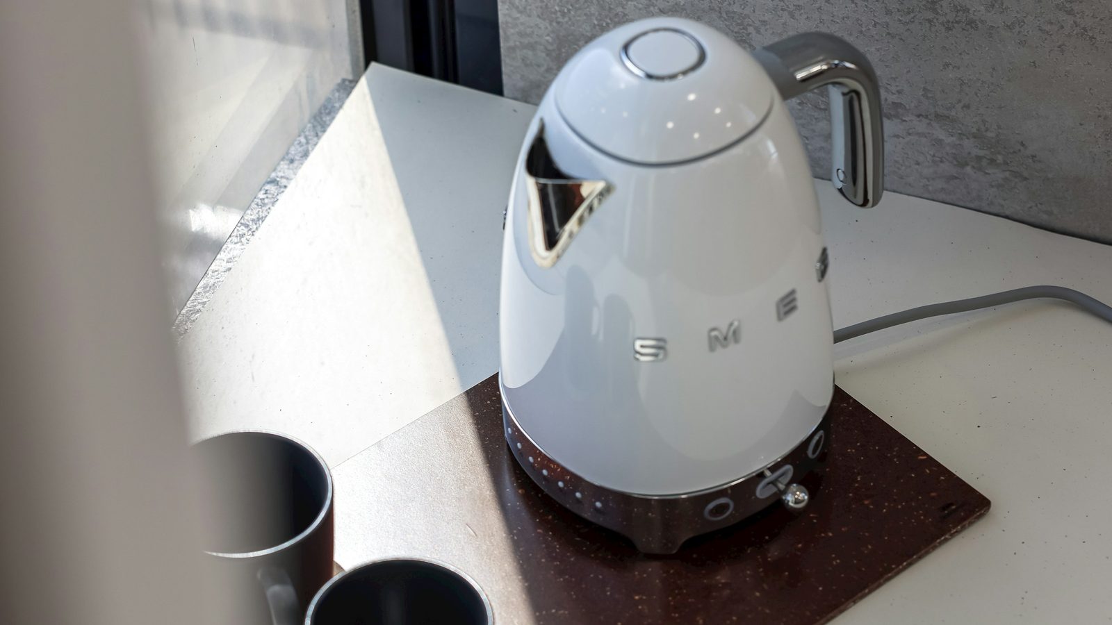 Hvid Smeg elkedel på køkkenbord med kopper og vindueslys