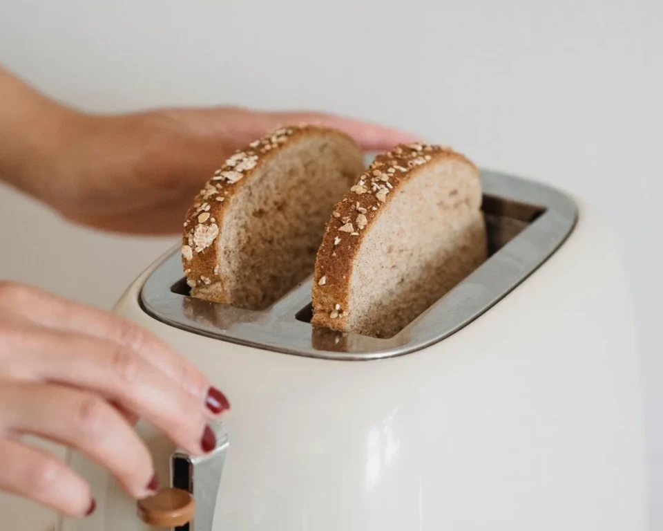 Skiver af fuldkornsbrød i en cremefarvet retrotoaster på et lyst køkkenbord