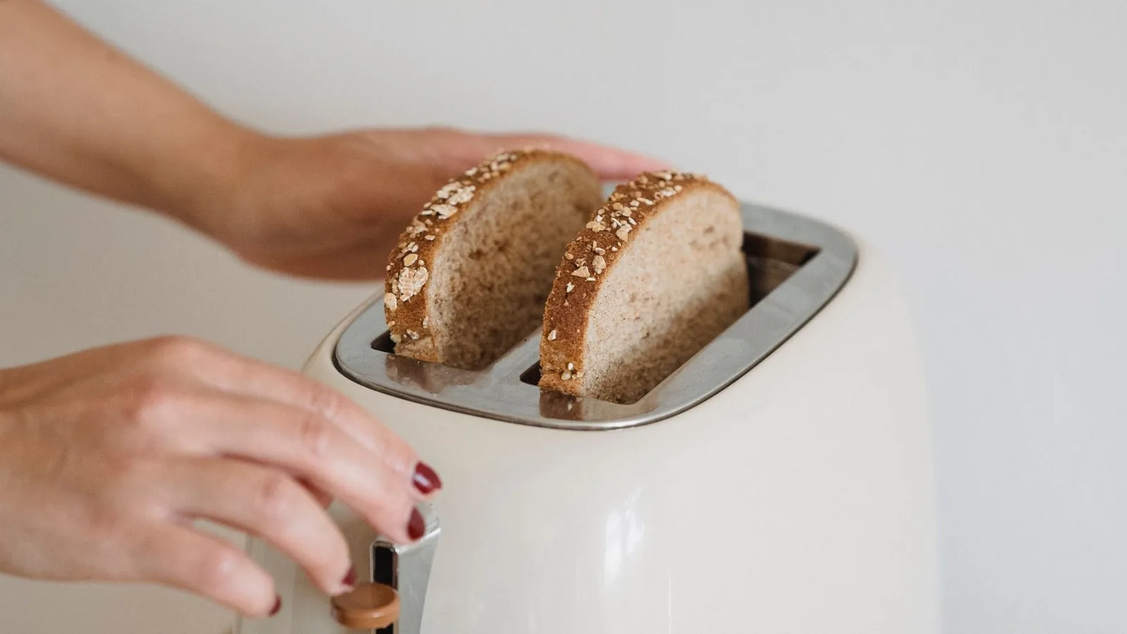 Skiver af fuldkornsbrød i en cremefarvet retrotoaster på et lyst køkkenbord