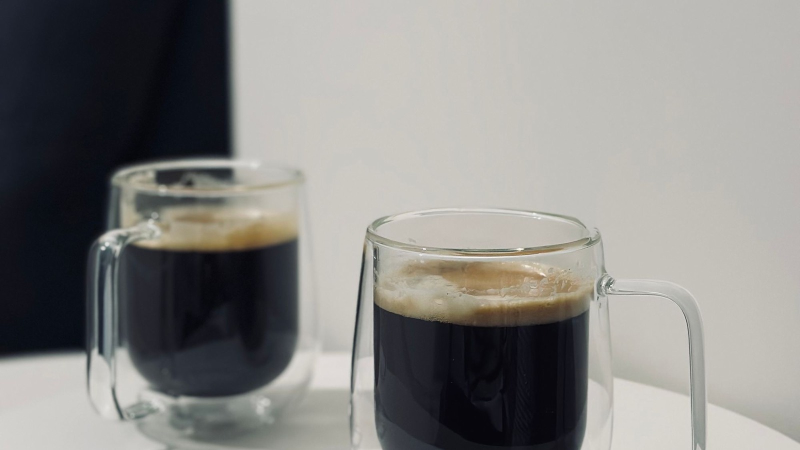 To dobbeltvæggede kaffeglas på et lyst bord