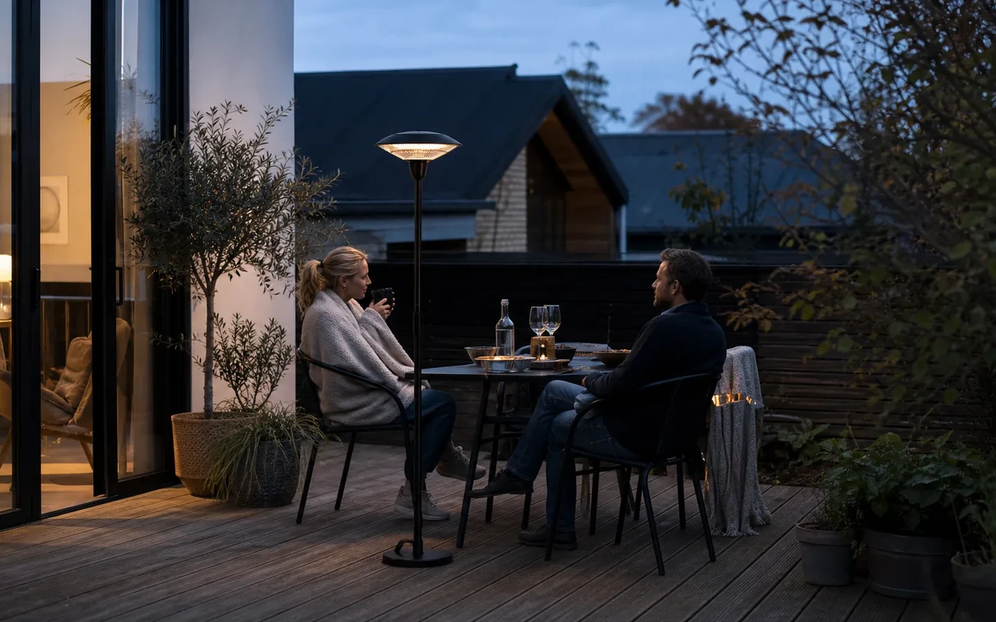 Par på en dansk terrasse en kølig sensommeraften med en diskret terrassevarmer