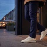 Mand i navy bukser og hvide sneakers på vej fra kontor ud i byen