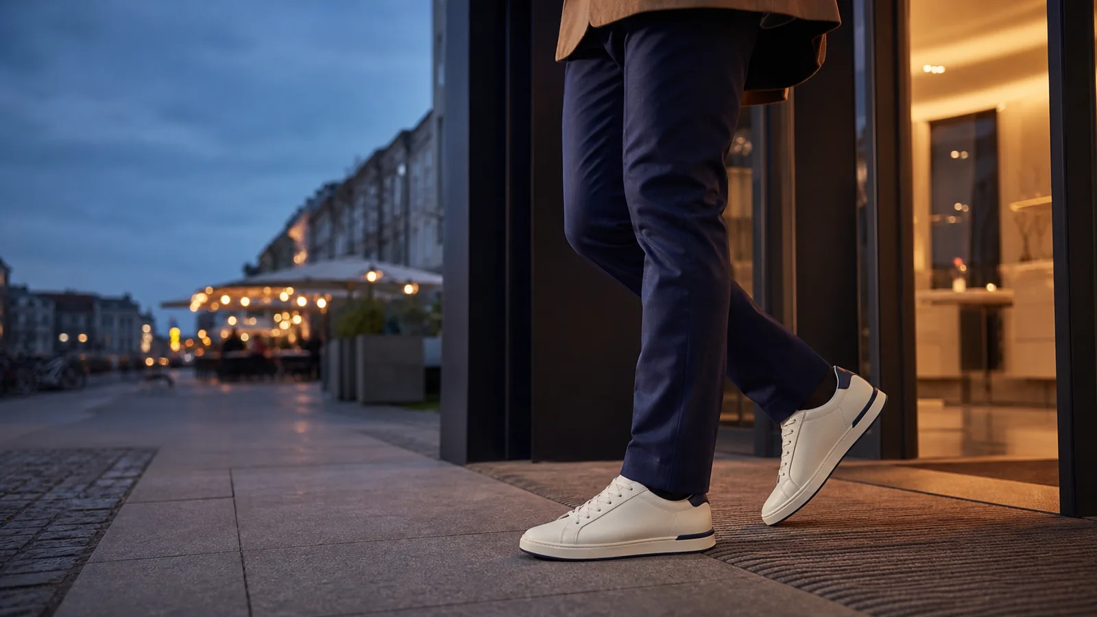 Mand i navy bukser og hvide sneakers på vej fra kontor ud i byen